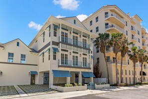 A multi-story hotel with balconies, a covered entrance, and palm trees.