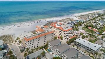 A coastal hotel with multiple buildings, a beach, and clear blue waters.