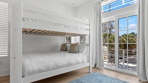 Un letto a castello con vista su palme e un balcone.
