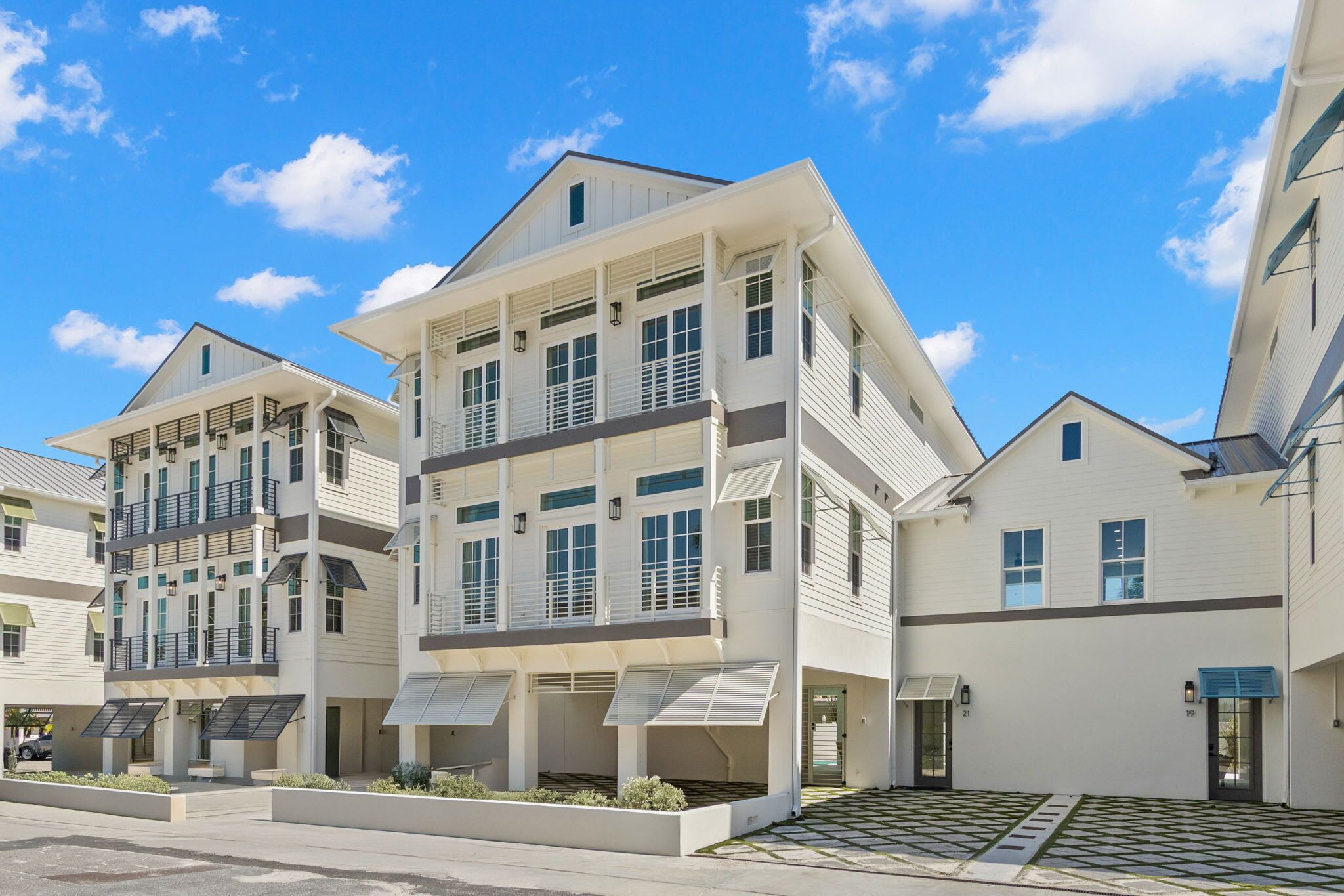 A modern multi-story residential building with a flat roof, large windows, and a covered outdoor area.