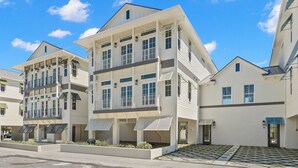 Un edificio residenziale moderno a più piani con tetto piatto, ampie finestre e una zona esterna coperta.