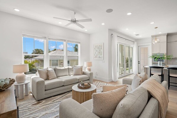 A modern living room with a sofa, coffee table, and a dining area with a table and chairs.