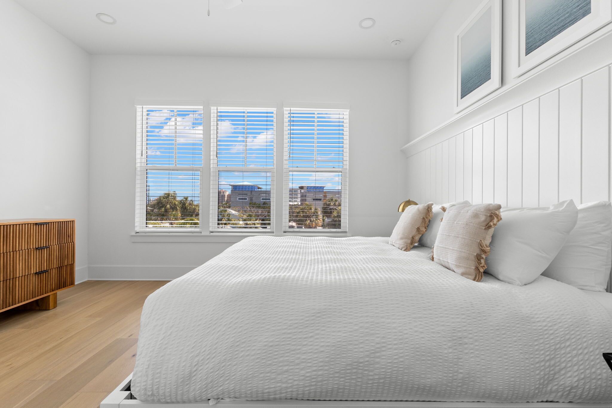 Une chambre avec un grand lit, une commode en bois et une fenêtre donnant sur la ville.