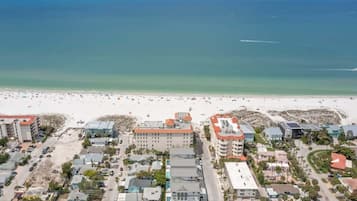 A coastal town with a beach, buildings, and parked cars.
