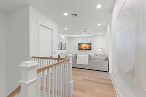 Ein modernes Interieur mit Treppe, einer Couch, einem Gemälde und einer Küchenzeile.