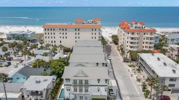 A coastal hotel with multiple floors, a swimming pool, and a beach view.