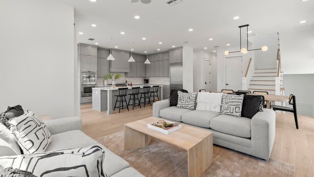 Ein modernes Wohnzimmer mit Sofa, Couchtisch und Essbereich mit Treppe.