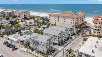 A coastal hotel with multiple floors, a parking lot, and a beach view.