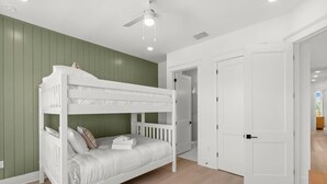 Ein Stockbett in einem Zimmer mit grünen Wänden, einer weißen Tür und einem Deckenventilator.