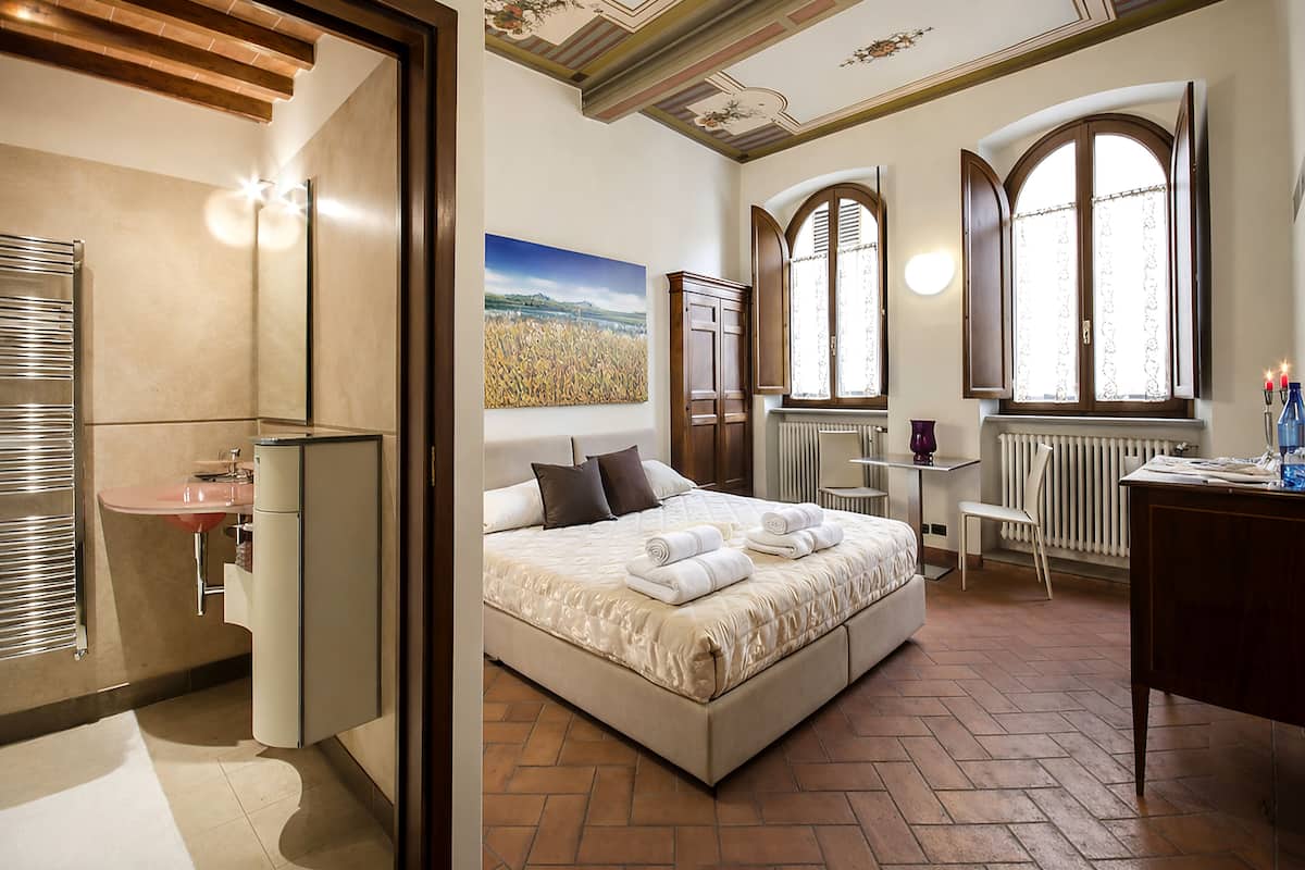 Un dormitorio con cama, escritorio, radiador y ventana.