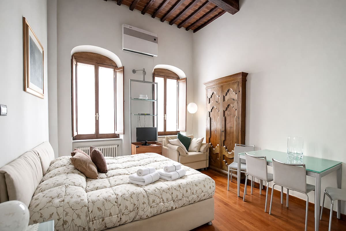 Un dormitorio con cama, escritorio, silla, armario y televisor.