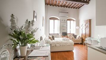 Un dormitorio espacioso con una cama grande, una zona de estar con sofá y un comedor con mesa y sillas.