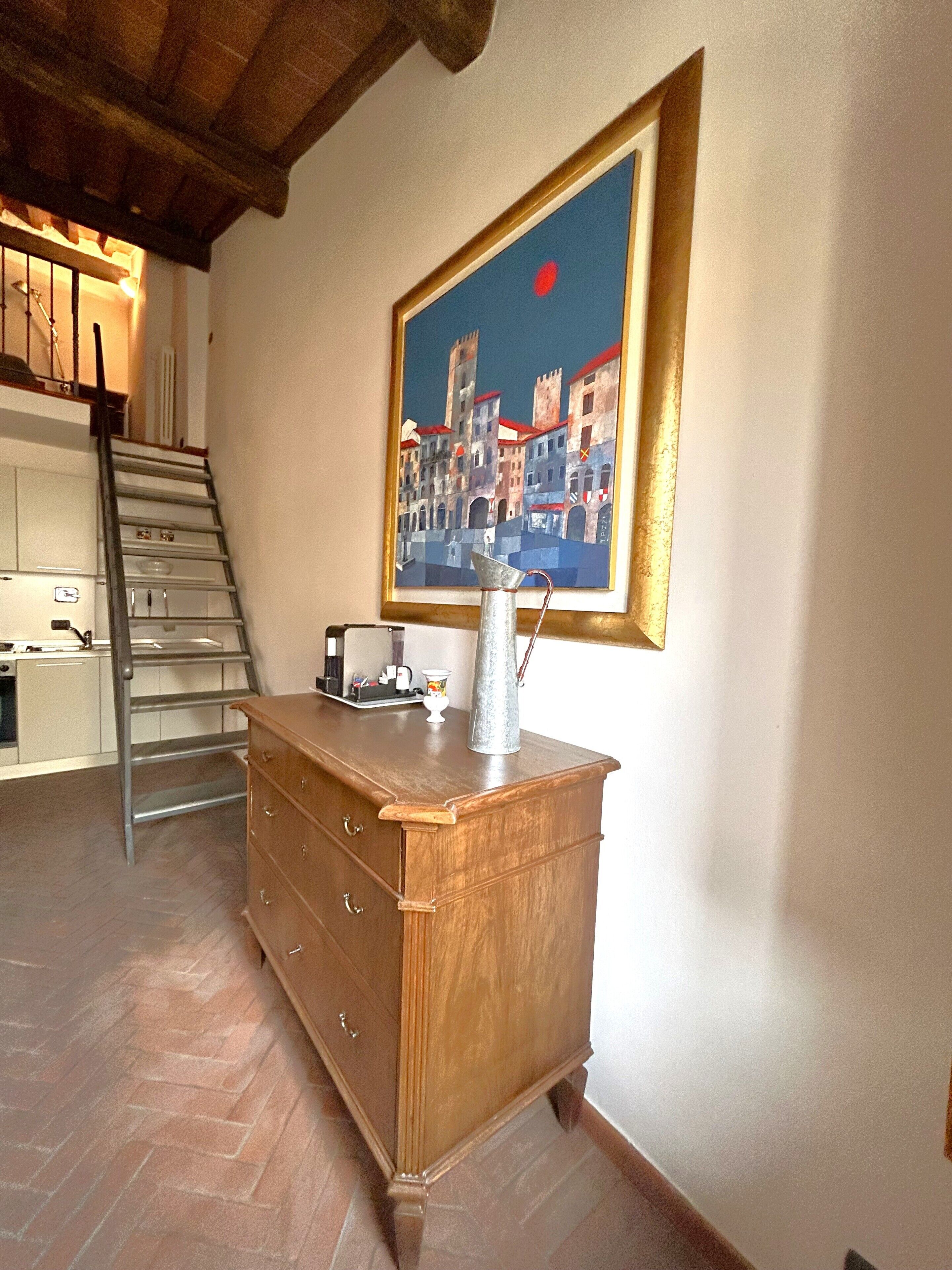A kitchen with a wooden cabinet, a ladder, and a painting of a cityscape on the wall.