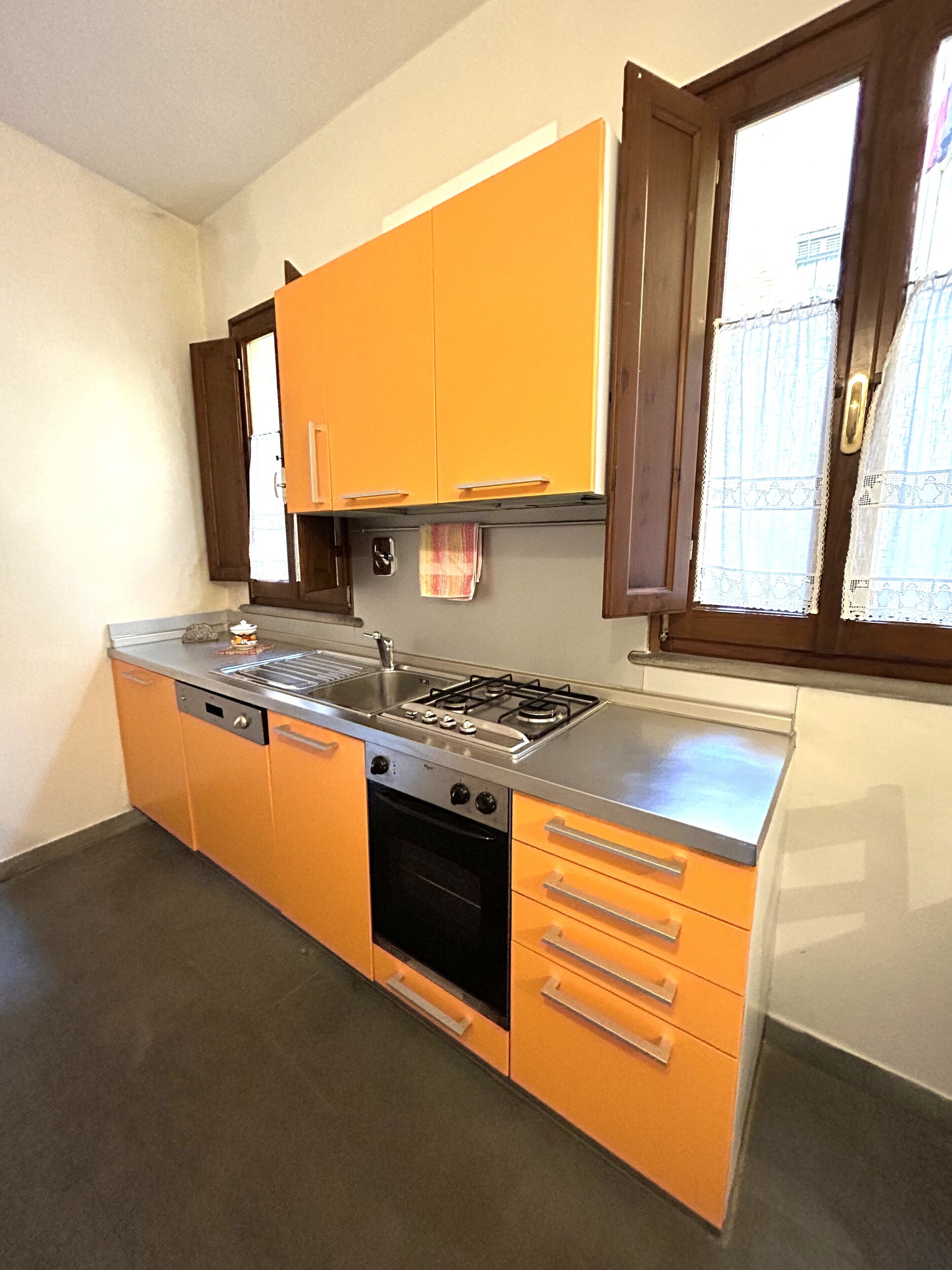 Una cocina compacta con armarios color naranja, una estufa a gas y un horno empotrado.