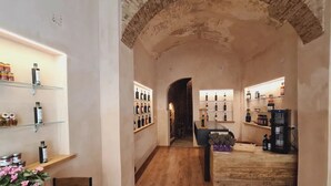 Un pasillo estrecho con suelo de madera, estantes con botellas a ambos lados y un arco de ladrillo al final.