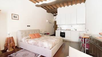 Une chambre dotée d’un grand lit, d’une petite kitchenette et d’un coin repas.