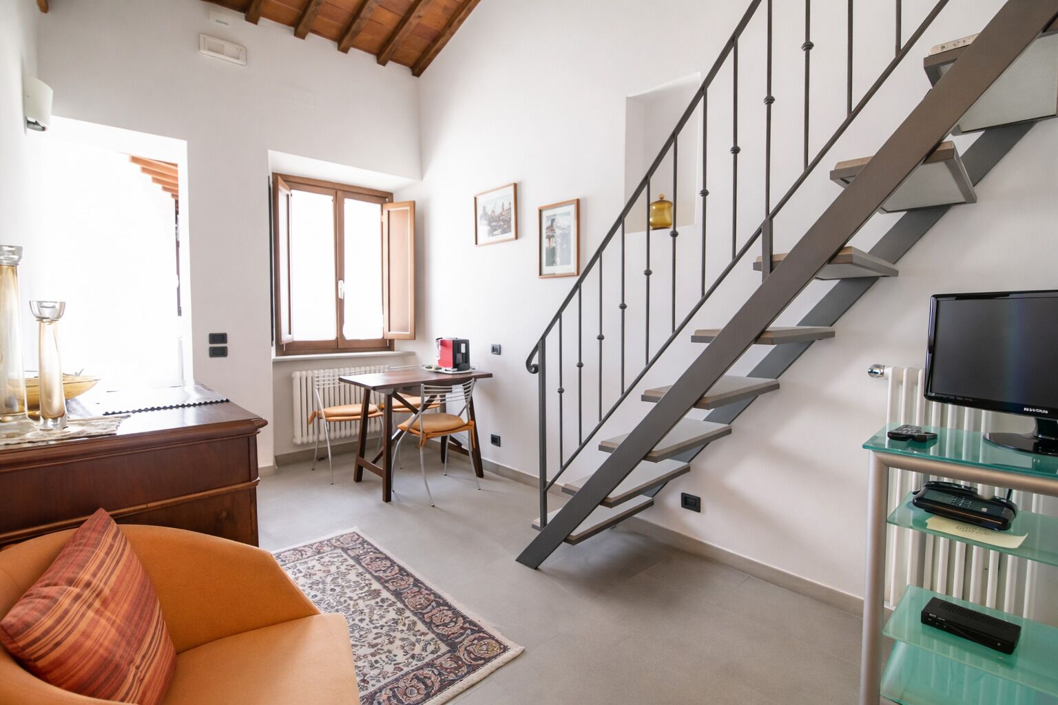A modern living room with a staircase, a dining area, and a sofa.