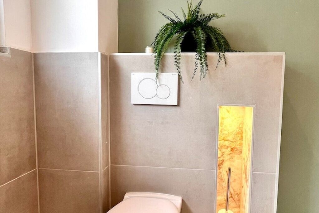 Un bagno con un water, un portasciugamani e una pianta.
