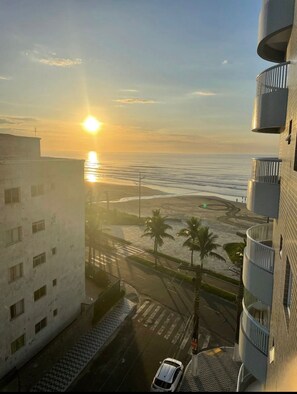 A high-rise building with a view of the ocean at sunset.