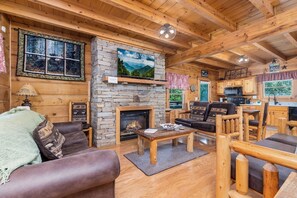 Un interior de cabaña acogedor con chimenea de piedra, muebles de madera y una pared de piedra.
