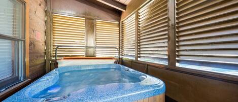 A hot tub with wooden walls and windows with blinds.
