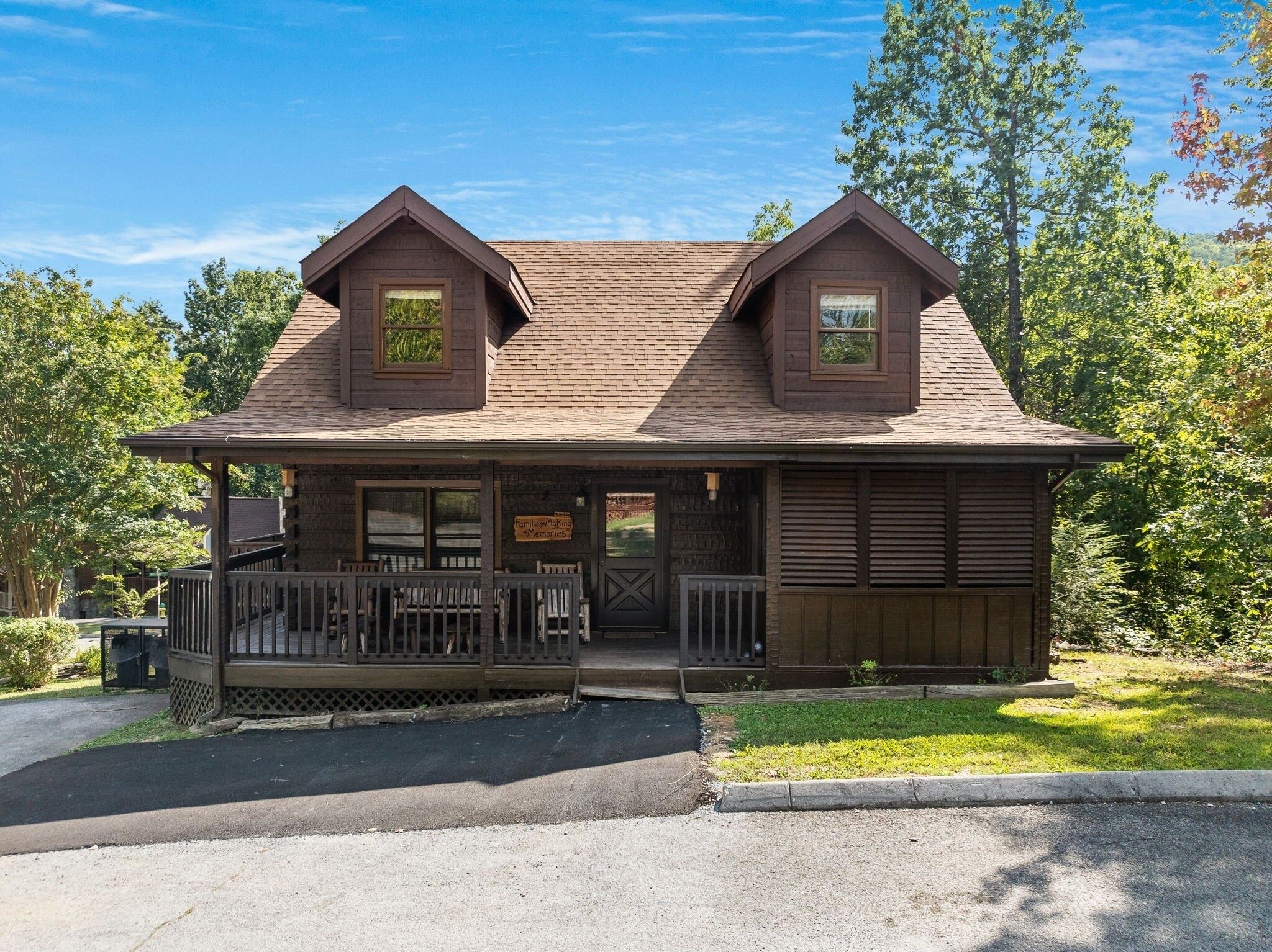 A rustic cabin with a front porch, two dormer windows, and a sign reading "Family Making Memories."