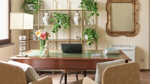 A modern living room with a wooden desk, two armchairs, a bookshelf with decorative items, and a large mirror on the wall. - Residenza Mondragone  (Florence)