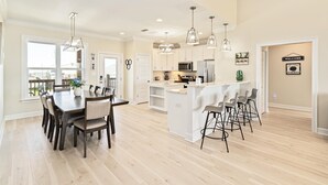 A spacious kitchen with a central island, white cabinetry, and pendant lighting. - Purple Paradise - 2536 Bienville Blvd 4 Bedroom Home by RedAwning (Dauphin Island)