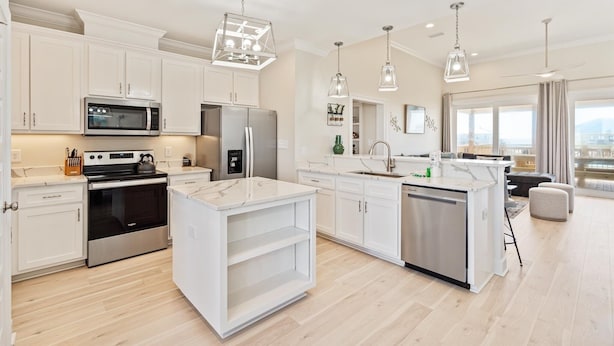 A modern kitchen with white cabinetry, stainless steel appliances, and pendant lighting. - Purple Paradise - 2536 Bienville Blvd 4 Bedroom Home by RedAwning (Dauphin Island)