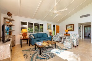 A spacious living room with a blue sofa, a coffee table, and patterned rugs.