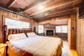 Ein Schlafzimmer einer Holzhütte mit einem Bett, einem Kamin und einem Fenster.