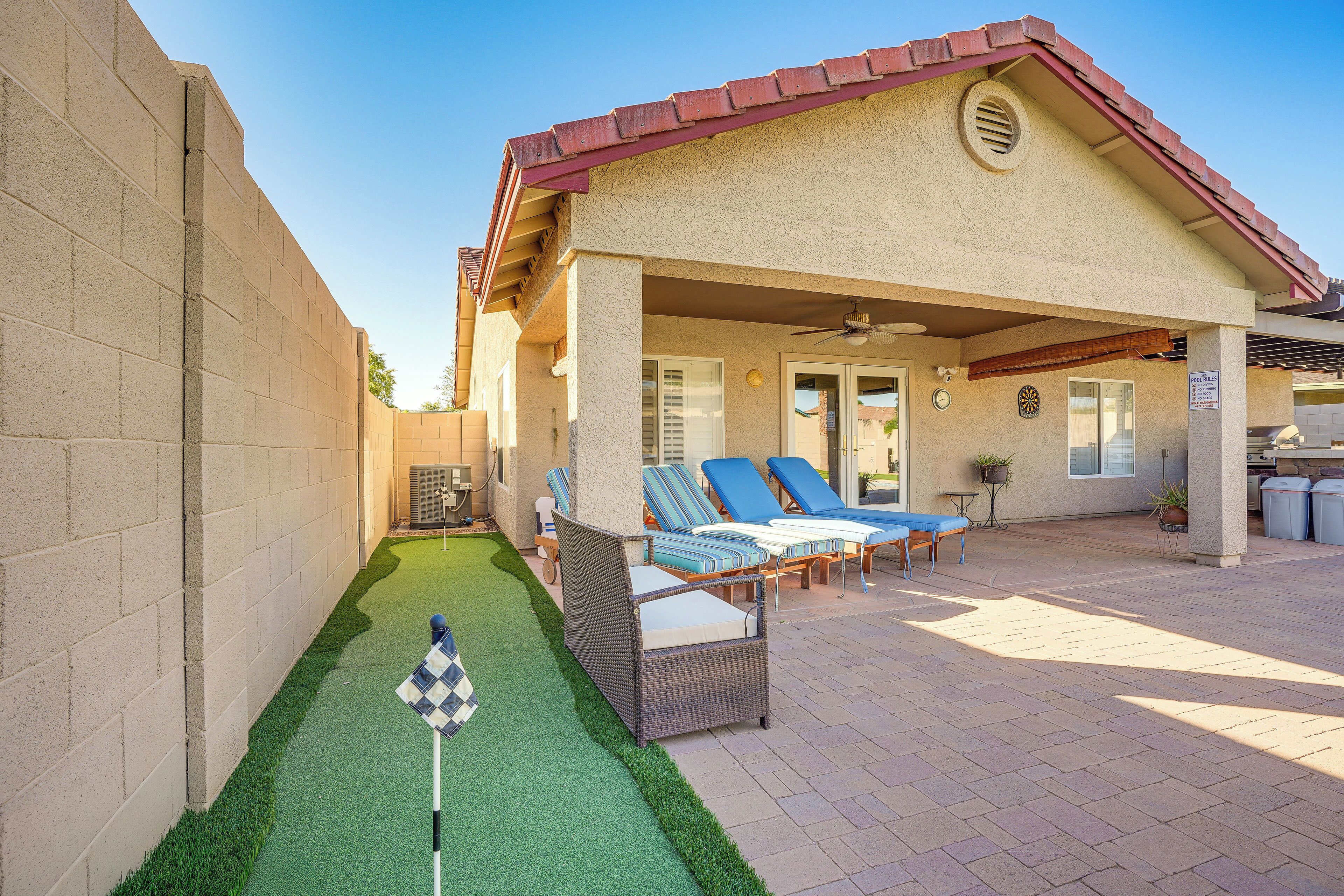 A residential property with a patio area featuring outdoor furniture, a pool, and a well-maintained lawn.