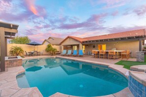 A swimming pool with a patio area, outdoor seating, and a covered section with a bar.
