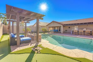 A backyard with a swimming pool, patio furniture, and a pergola.