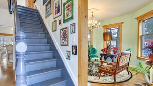 A staircase with blue steps and a wooden handrail, leading to a room with a chandelier, a round table, and a chair. - Victorian Lake Oasis | Hot Tub | Private Lakefront (Damascus)