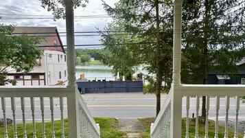 A view from a porch with a staircase leading to a street. There are houses and a body of water in the background.