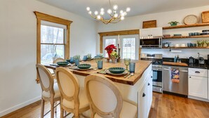 A kitchen with a central island, wooden chairs, a chandelier, and built-in appliances. - Victorian Lake Oasis | Hot Tub | Private Lakefront (Damascus)
