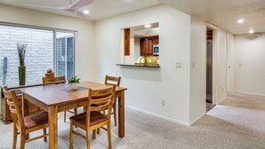 A dining area with a wooden table and chairs, a ceiling fan, and a view through a glass door. - Tucson Townhome w/ Mountain View, Pool Access! (Tucson)