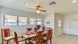 Une salle à manger avec une table en bois, des chaises et un ventilateur de plafond.