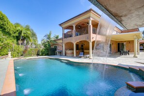 Relax by the pool surrounded by a water feature and lounge chairs.