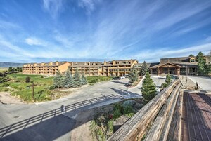 A multi-story hotel with a central courtyard, surrounded by greenery and a parking area.