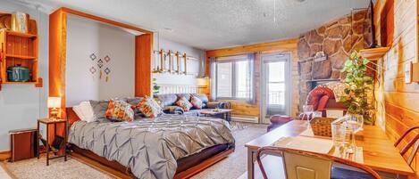 A bedroom with a bed, a dining table, and a fireplace.