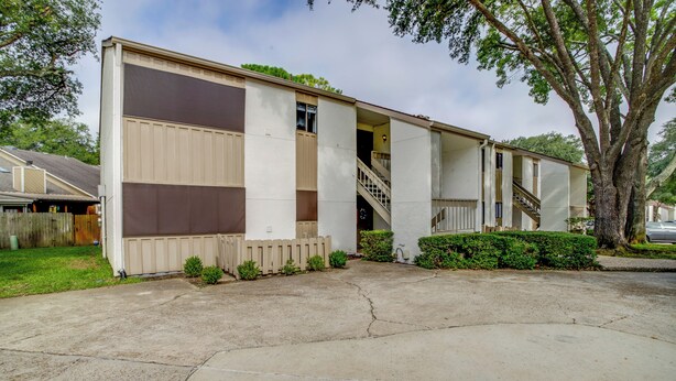 A two-story mobile home with a front porch, a staircase, and a large tree in the background. - Chic Montgomery Condo w/ Balcony + Pool Access! (Montgomery)