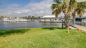 A marina with boats docked, a small building with a white roof, and a palm tree in the foreground. - Chic Montgomery Condo w/ Balcony + Pool Access! (Montgomery)