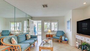 A living room with wicker furniture, a glass coffee table, and a television on a wooden stand. - Siesta Keys Home w/ Deck Half Mile to Turtle Beach (Siesta Key)
