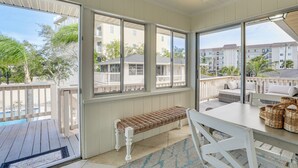 A sunlit room with large windows, a wooden bench, a table with baskets, and a view of neighboring buildings. - Siesta Keys Home w/ Deck Half Mile to Turtle Beach (Siesta Key)