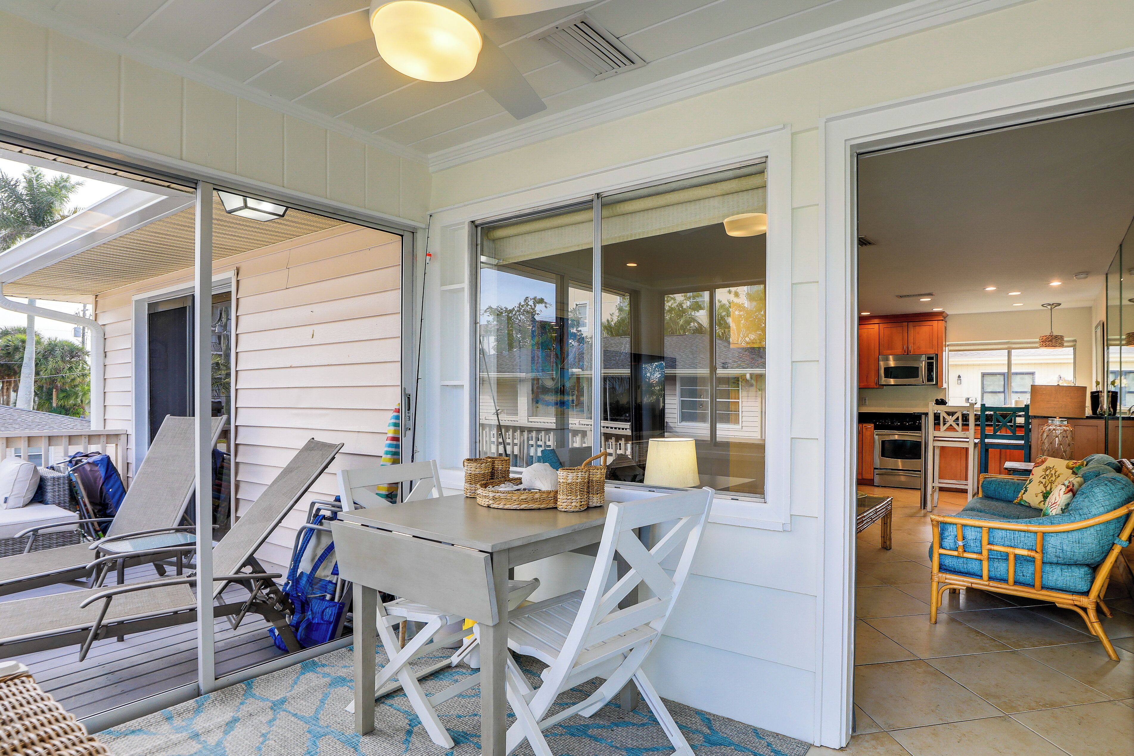 A covered patio with a table and chairs, a wicker basket, and a view into the house.