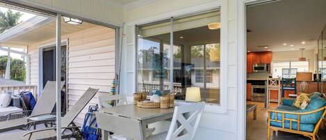 A covered patio with a table and chairs, a wicker basket, and a view into the house.