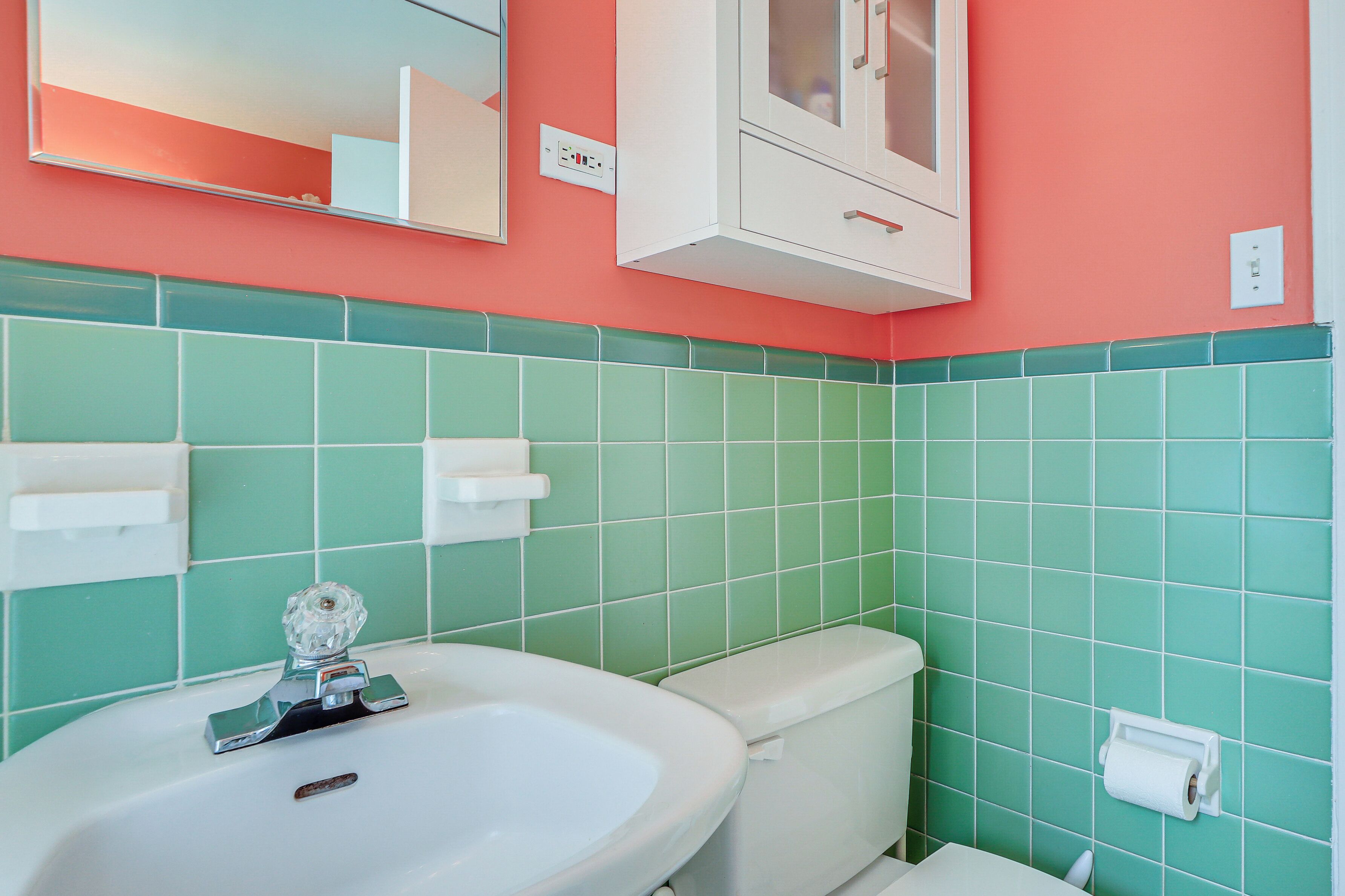 A bathroom with a white sink, a toilet, and a mirror above the sink.