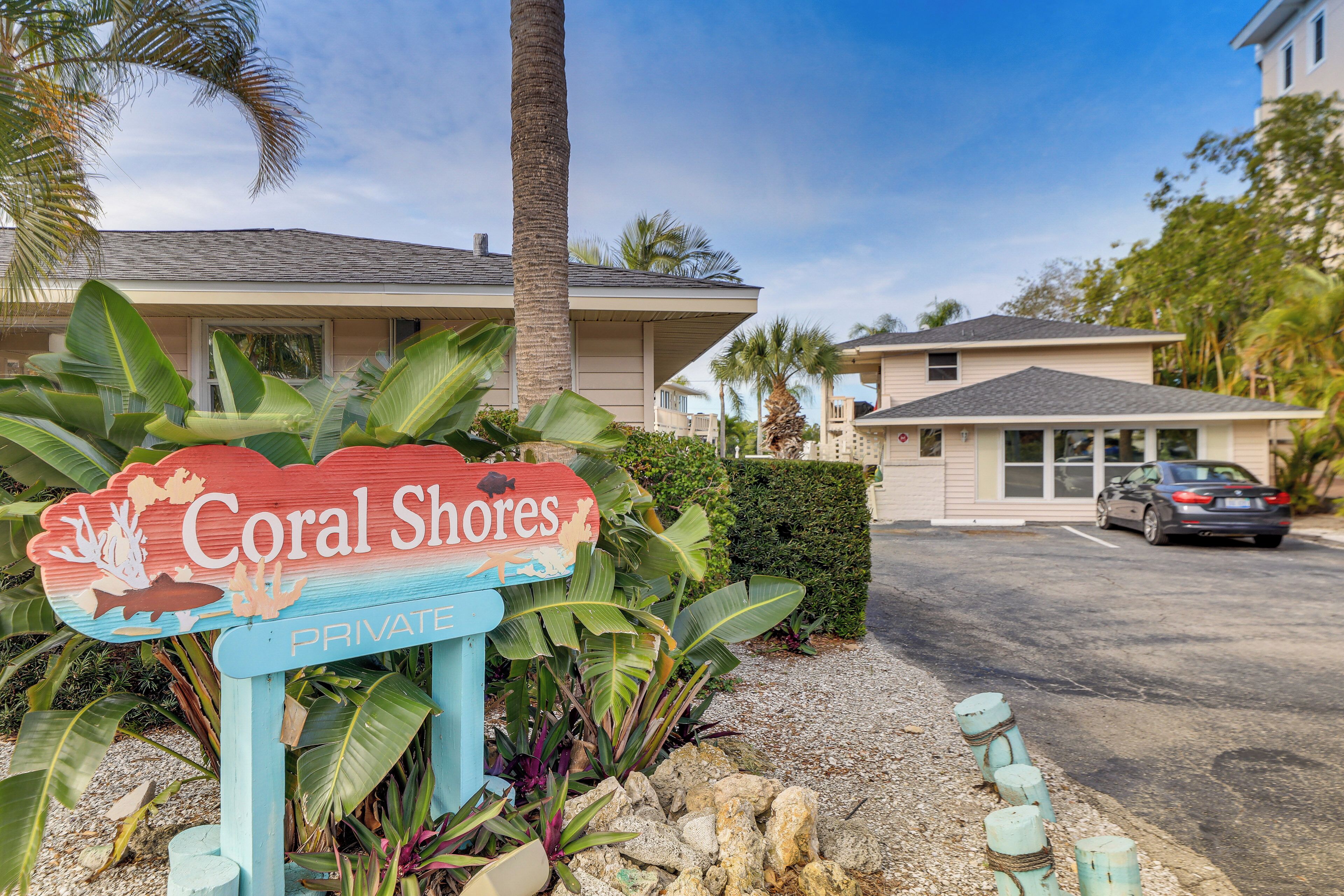 A sign for Coral Shores Private, a house with a garage, and a car parked in the driveway.